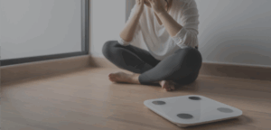 Giovane seduta accanto a una bilancia, immagine simbolica dei disturbi alimentari e del ruolo dei social network